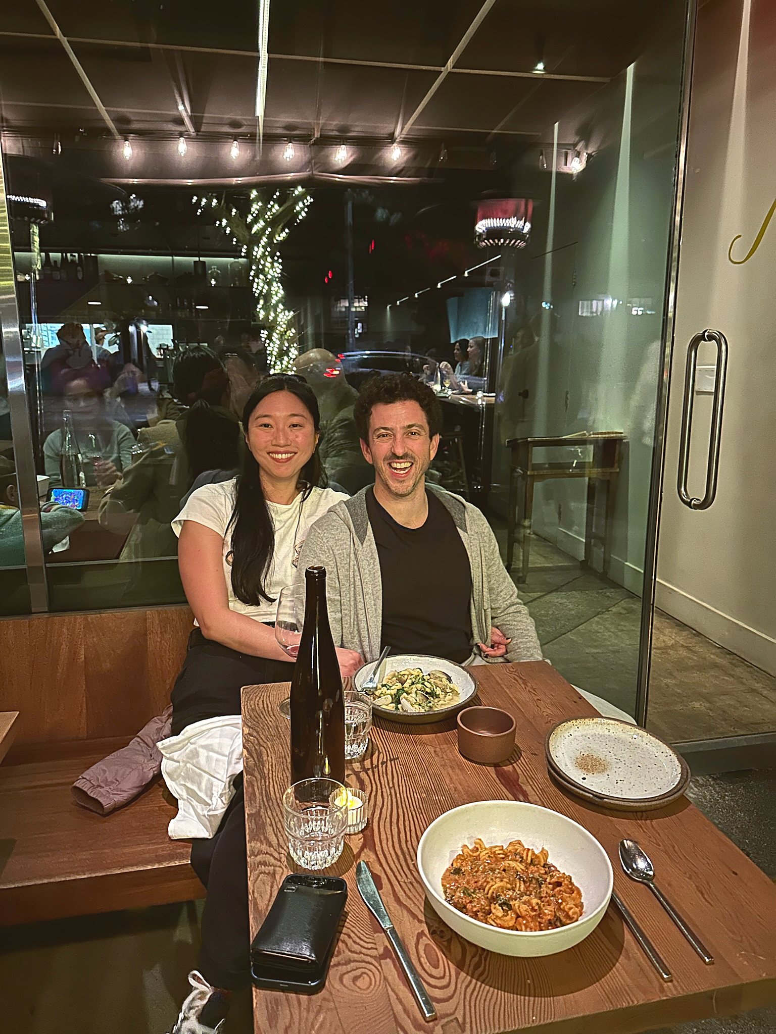 Andrew and Tracy side by side at a restaurant table, both smiling at the camera over dinner.
