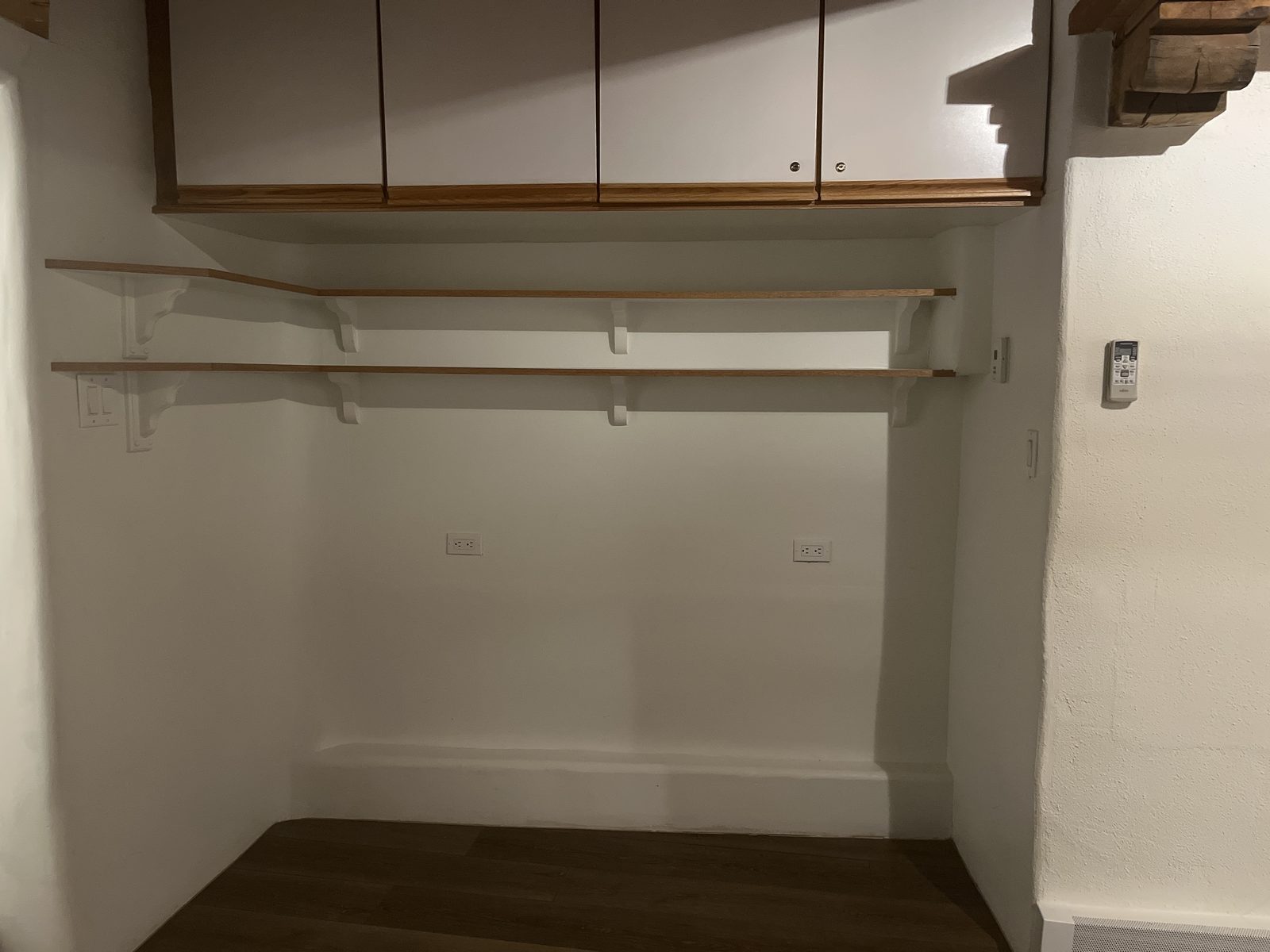 The alcove before the build: bare plastered walls, two oak shelves on brackets and a cabinet above, with nothing in the space where the bed would go.