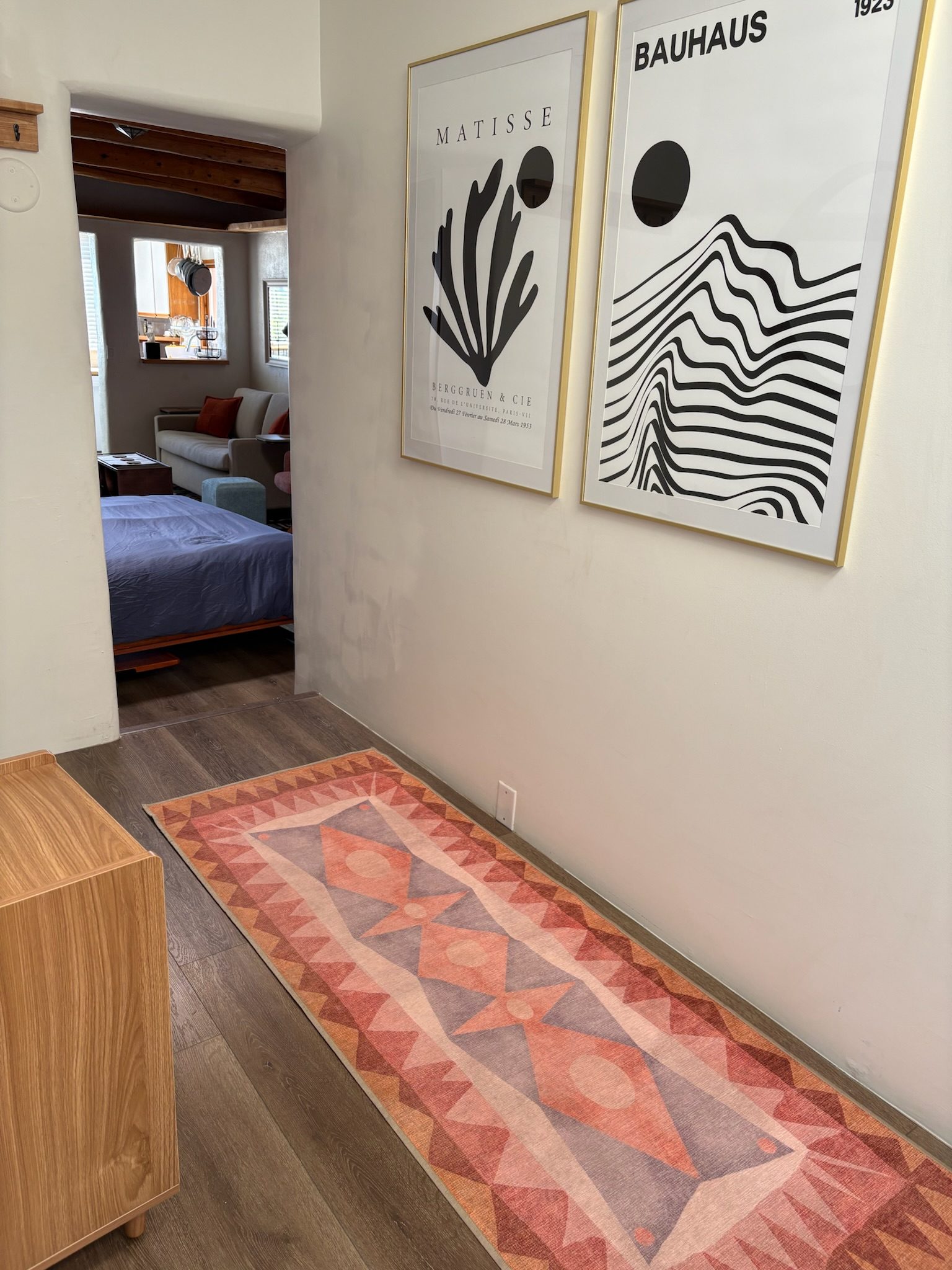 Just inside the casita's front door: a runner rug down the hall, framed prints on the wall, and the main room opening up beyond.