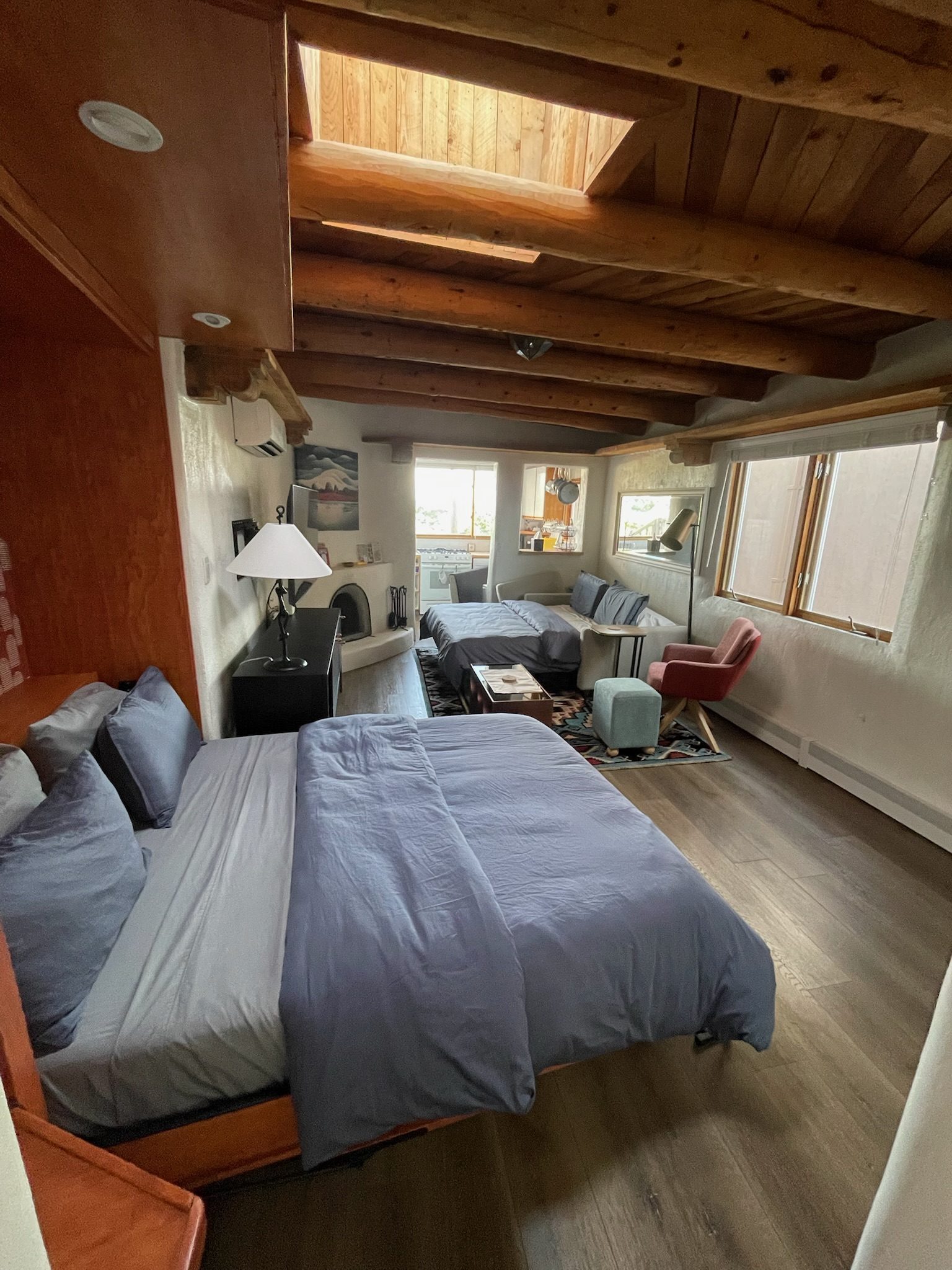The whole sleeping arrangement in one look: the queen bed in front, the queen sleeper made up by the kiva behind, vigas and the skylight above.