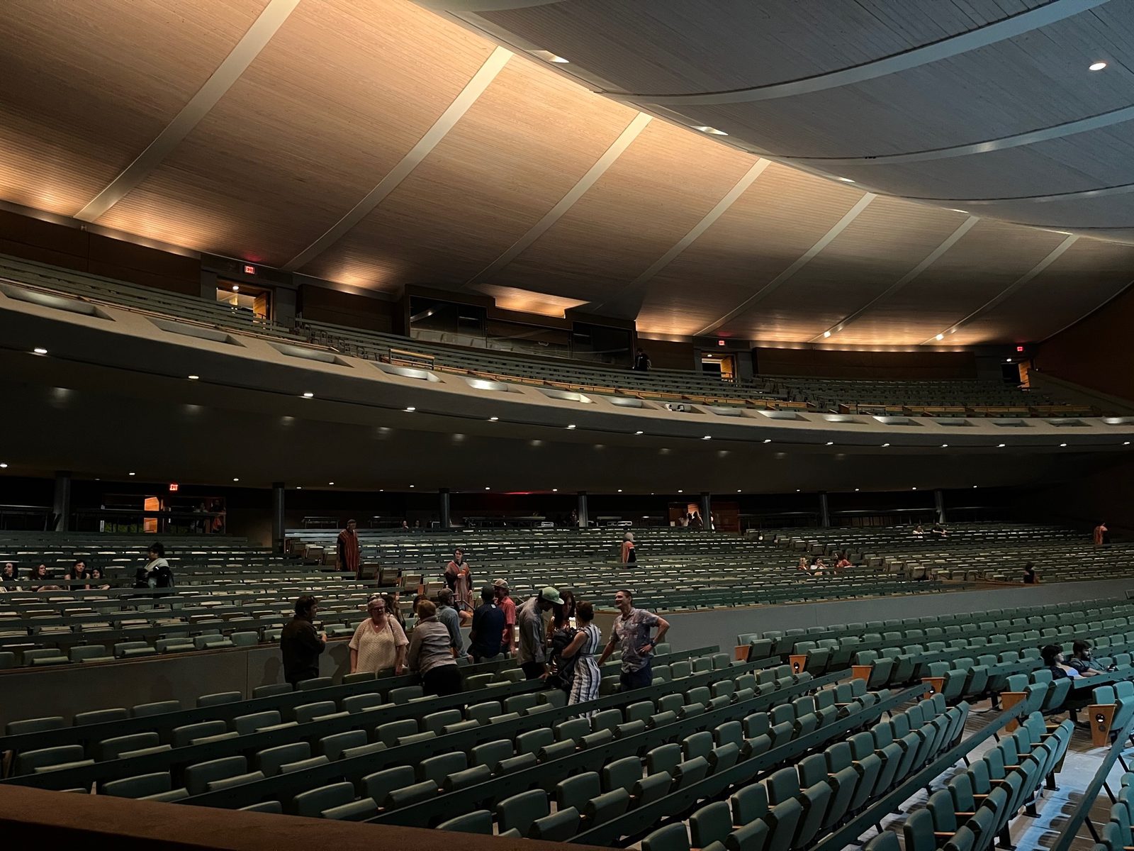 Inside the Santa Fe Opera house before curtain, the sweeping wood ceiling over rows of seats as people find their places.