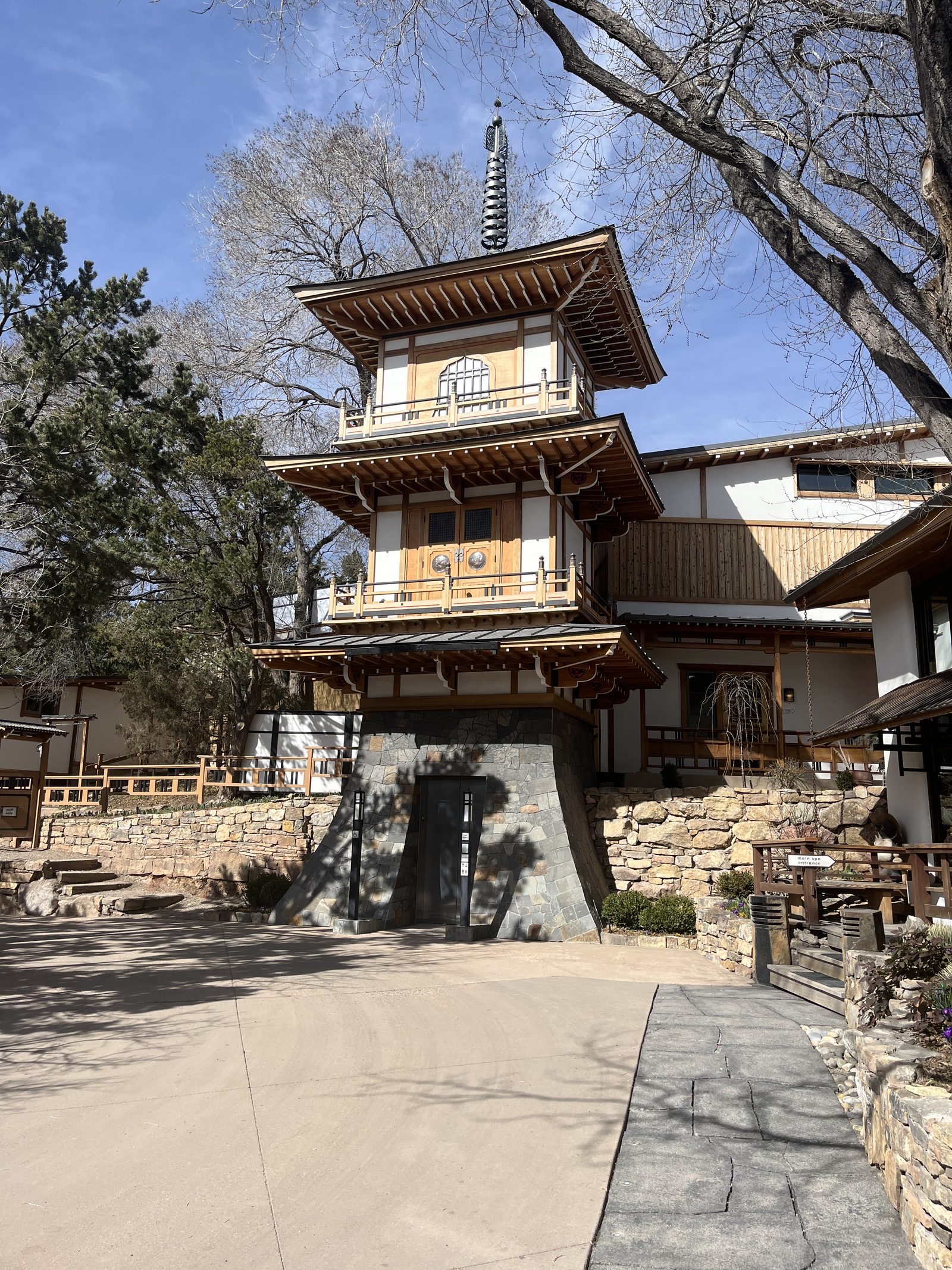 The pagoda tower at Ten Thousand Waves against bare spring branches and blue sky.