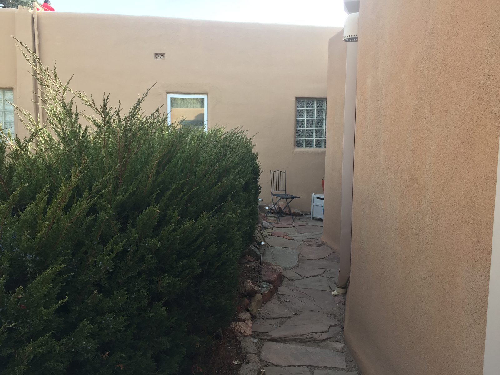 The compound on the first visit in 2018: a flagstone path between plastered walls, an overgrown juniper, and a single iron chair.