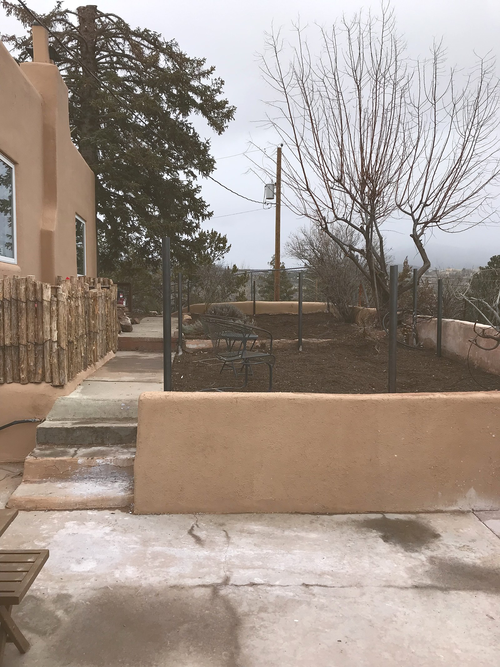 Winter 2021: the new coyote-pole fence up, fresh stucco on the walls, a planting bed turned over and waiting, and a new concrete terrace poured.