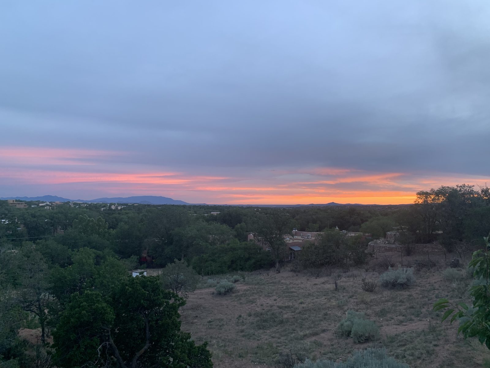 Sunset from the property: orange and pink cloud over the hills with the town in the trees below.
