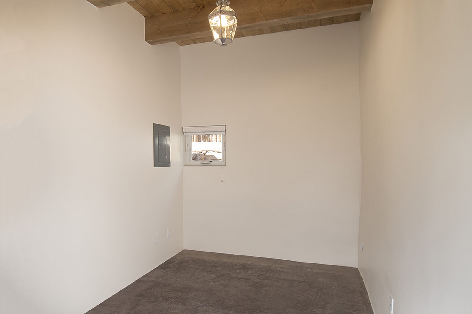 Unit A's bedroom with a beamed ceiling, a pendant light, carpet, and a window to the yard.