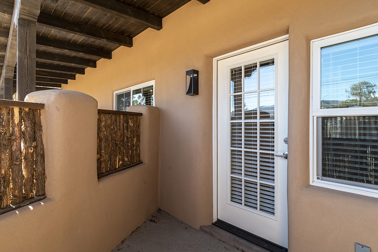 The entry to Unit A, a French door under the covered portal beside a coyote-pole gate.