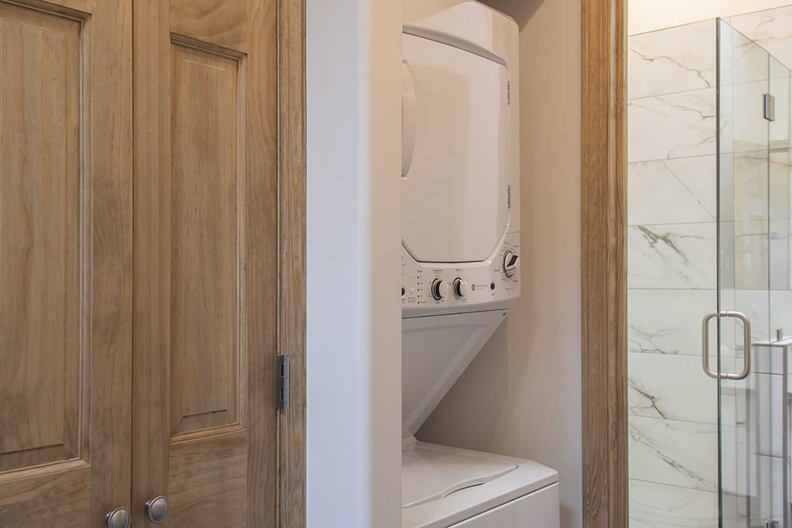 Unit A's in-unit stacked washer and dryer set behind a wood door beside the bathroom.