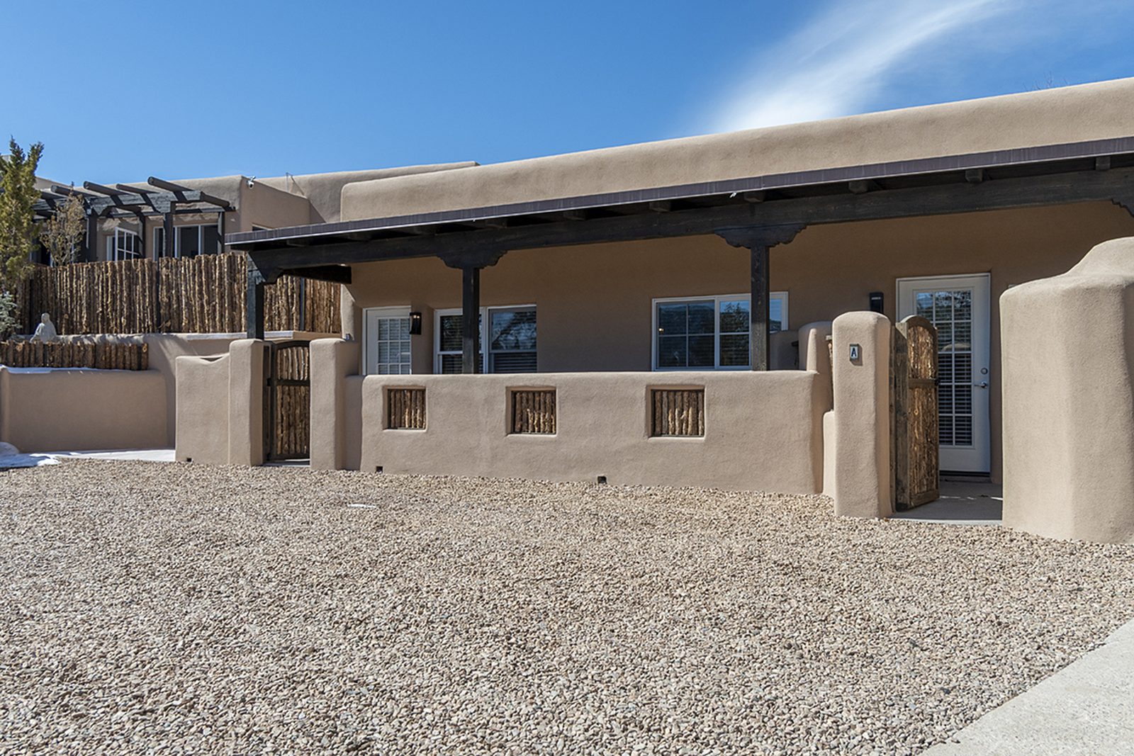 The covered portal running along the units, with stucco columns and a gravel yard beyond.