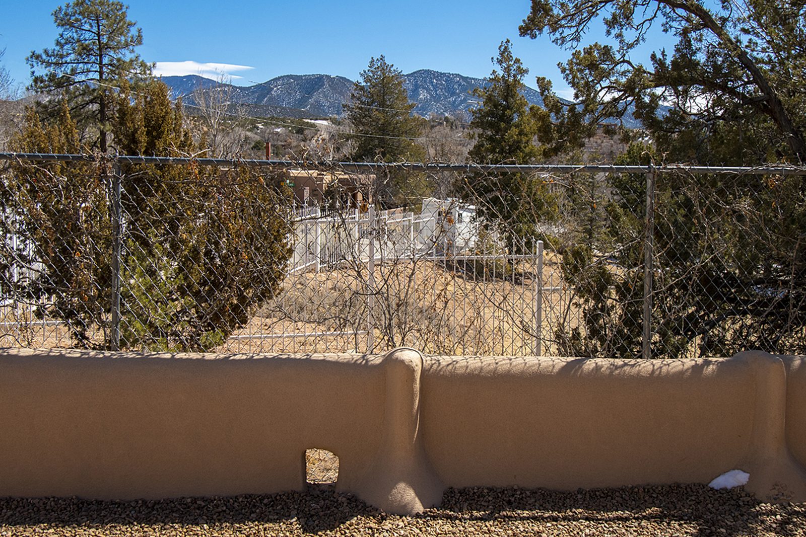The view from Unit A over a low adobe wall to pinon, juniper and the ridgeline beyond.