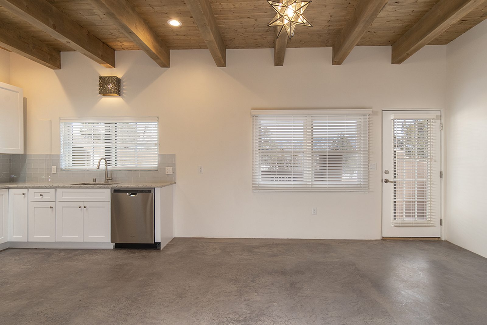 Unit B's open great room with a viga ceiling, the kitchen along one wall and a French door to the patio.