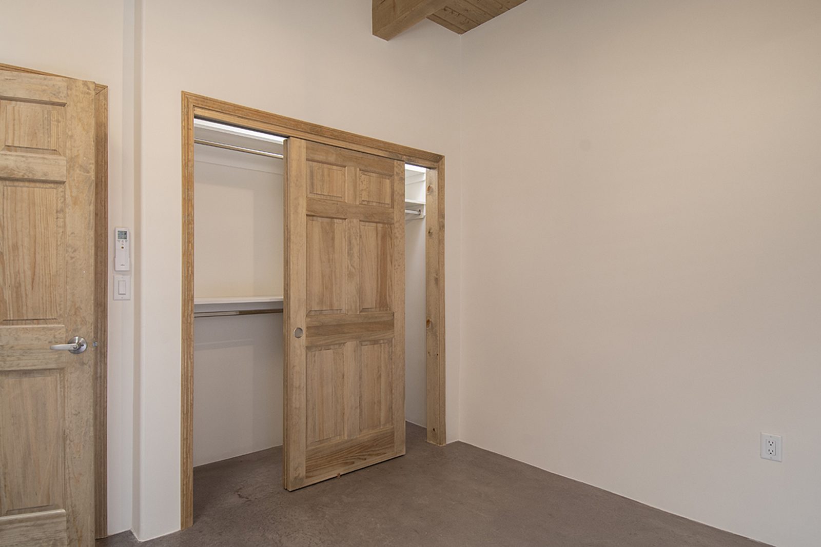 Unit B's second bedroom with a closet, a wood door, and concrete floors.