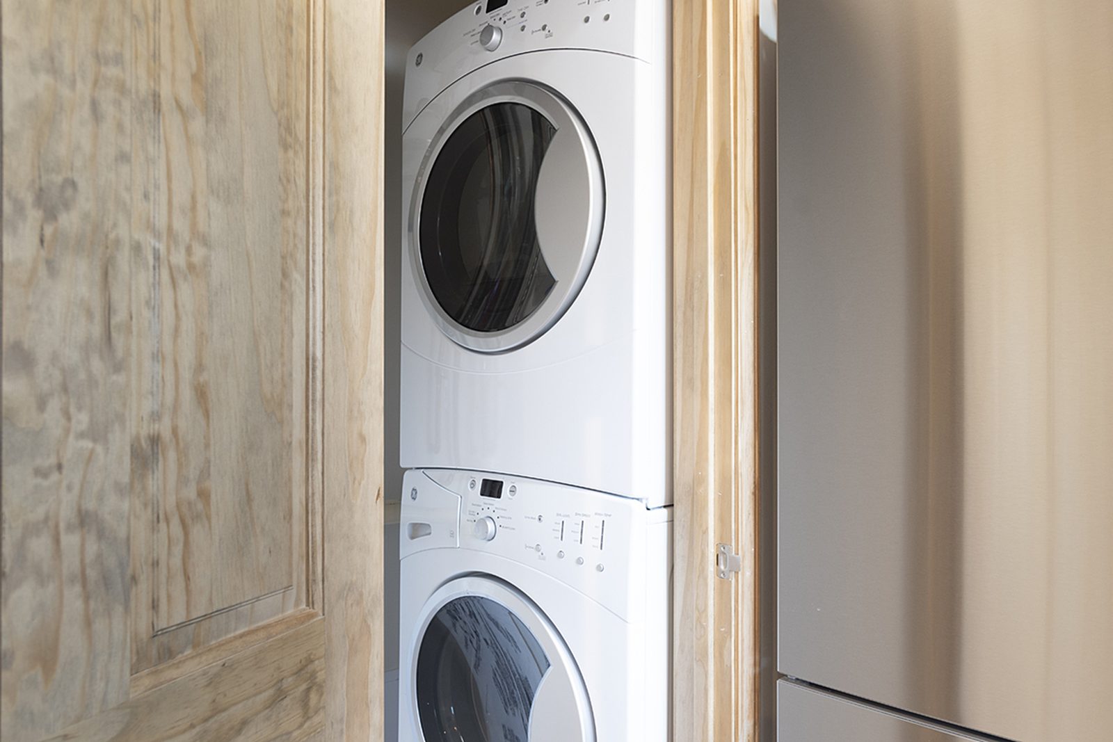 Unit B's in-unit stacked washer and dryer behind wood doors.
