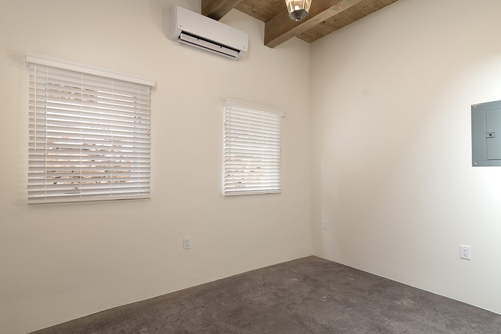 Unit B's primary bedroom with a mini-split unit, a window, and finished concrete floors.