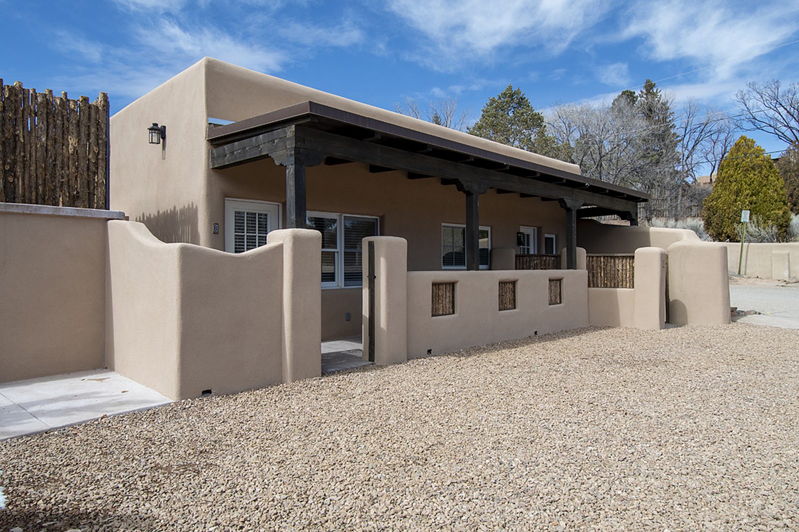 The long covered portal running the length of the units, stucco walls and gravel underfoot.