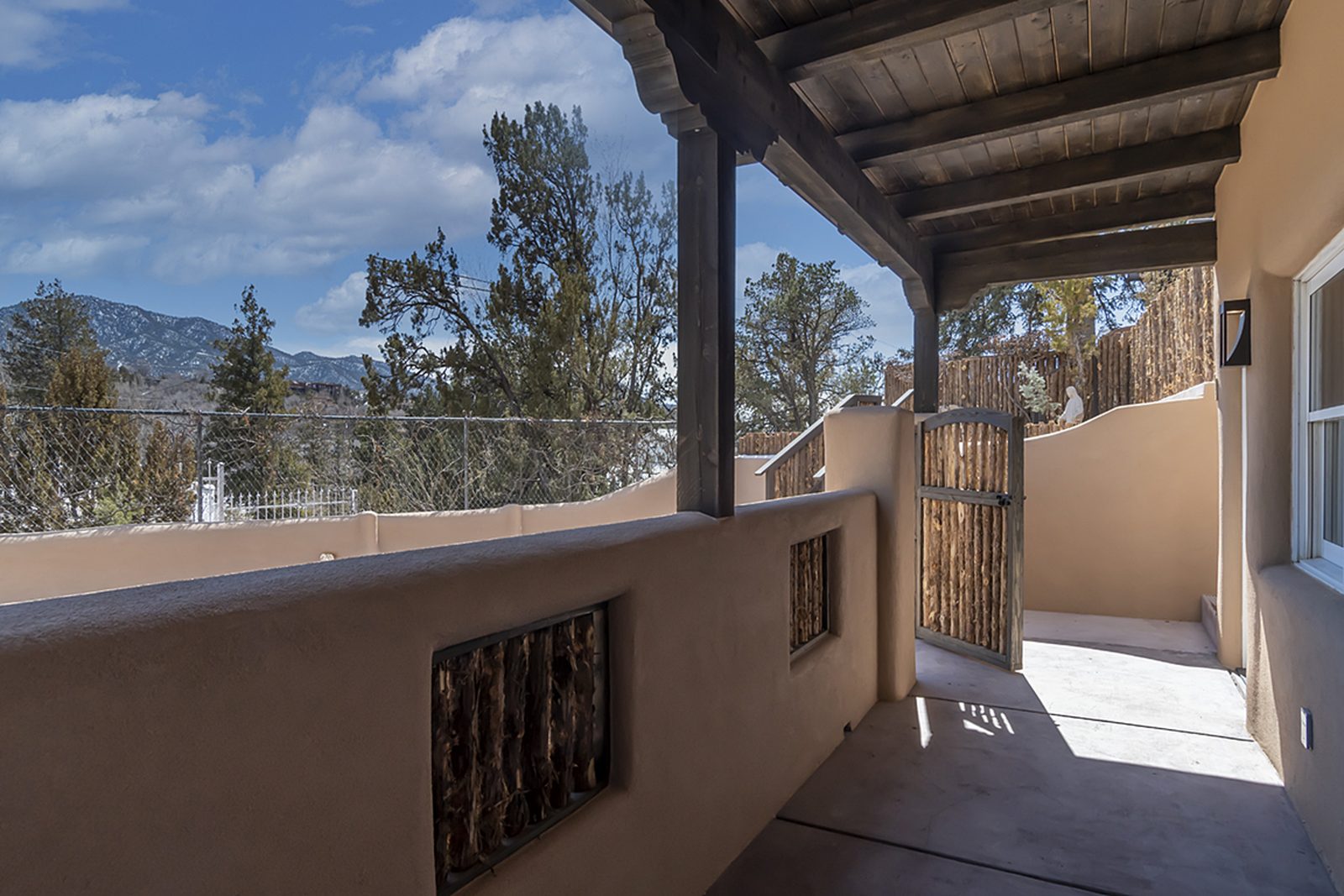 Unit B's covered portal looking out between stucco walls to the trees and mountains.