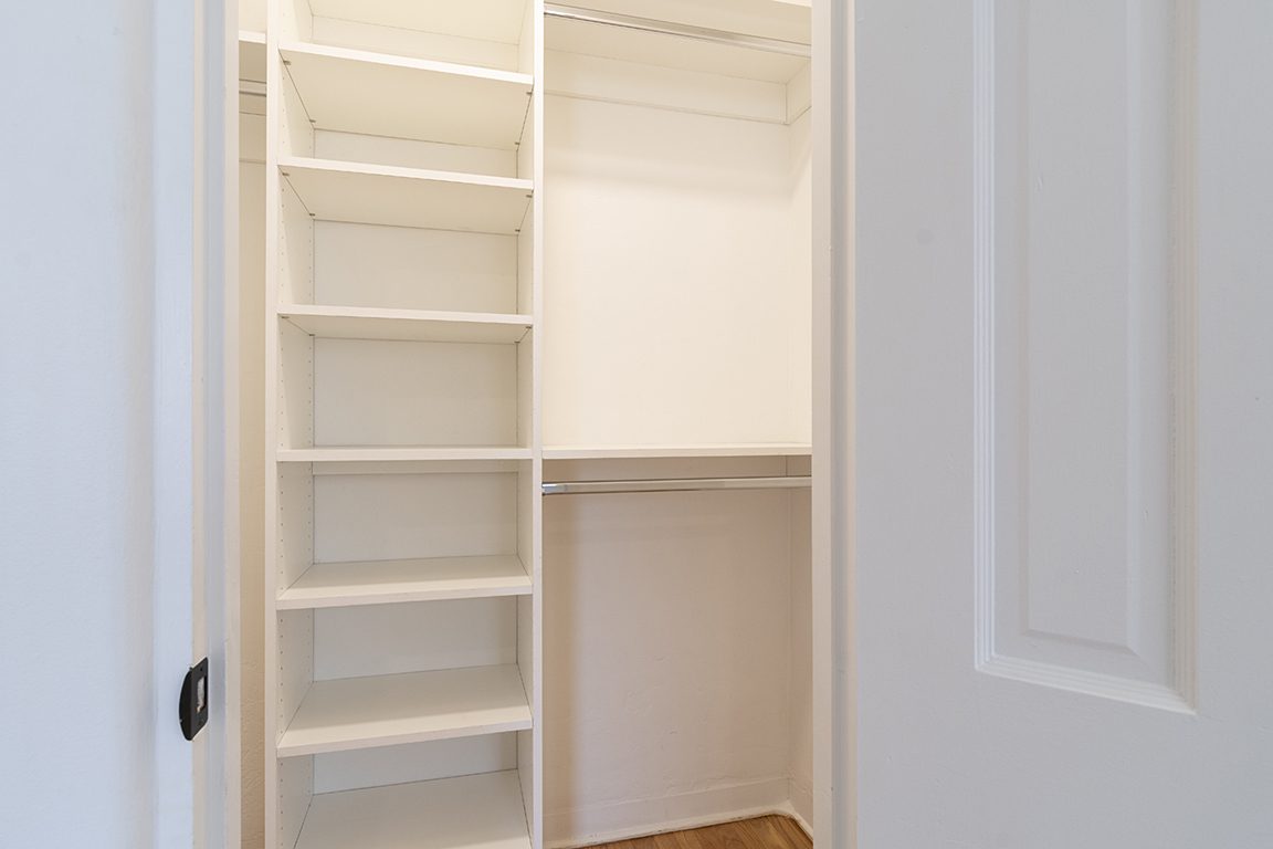 A fitted closet in Unit C's second bedroom, shelving and double hanging rails ready to fill.