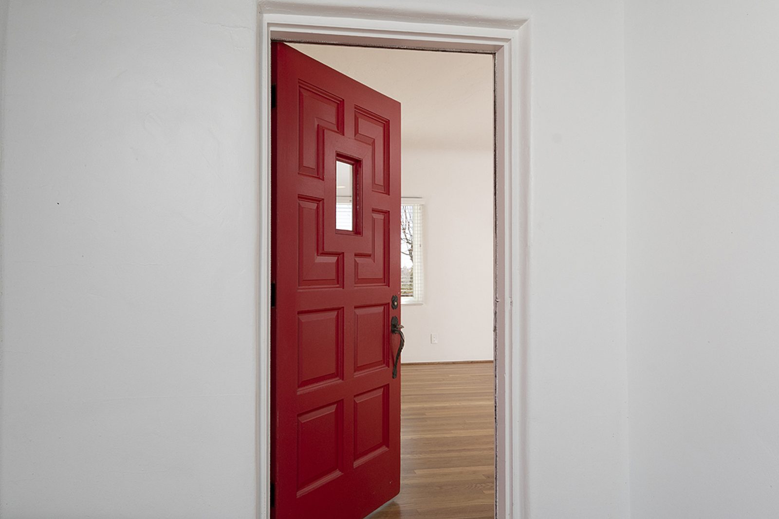 Unit C's red-painted front door standing open onto the hallway.