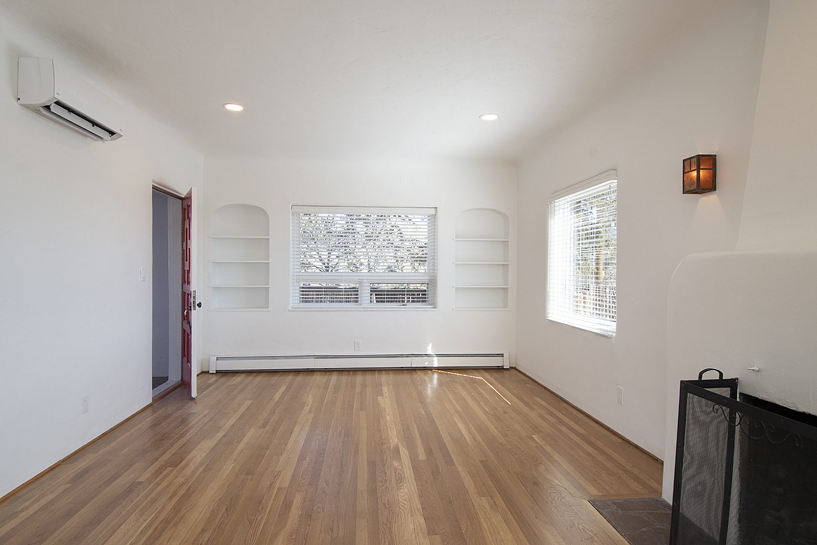 Unit C's great room from the far end, the corner fireplace and built-in shelves under a bank of windows.