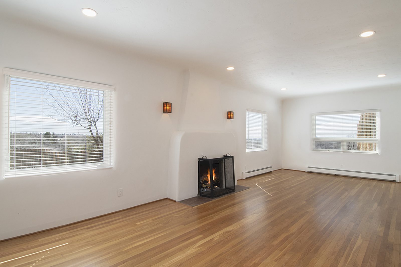 Unit C's great room with hardwood floors, a corner fireplace, built-in shelving and windows on two sides.