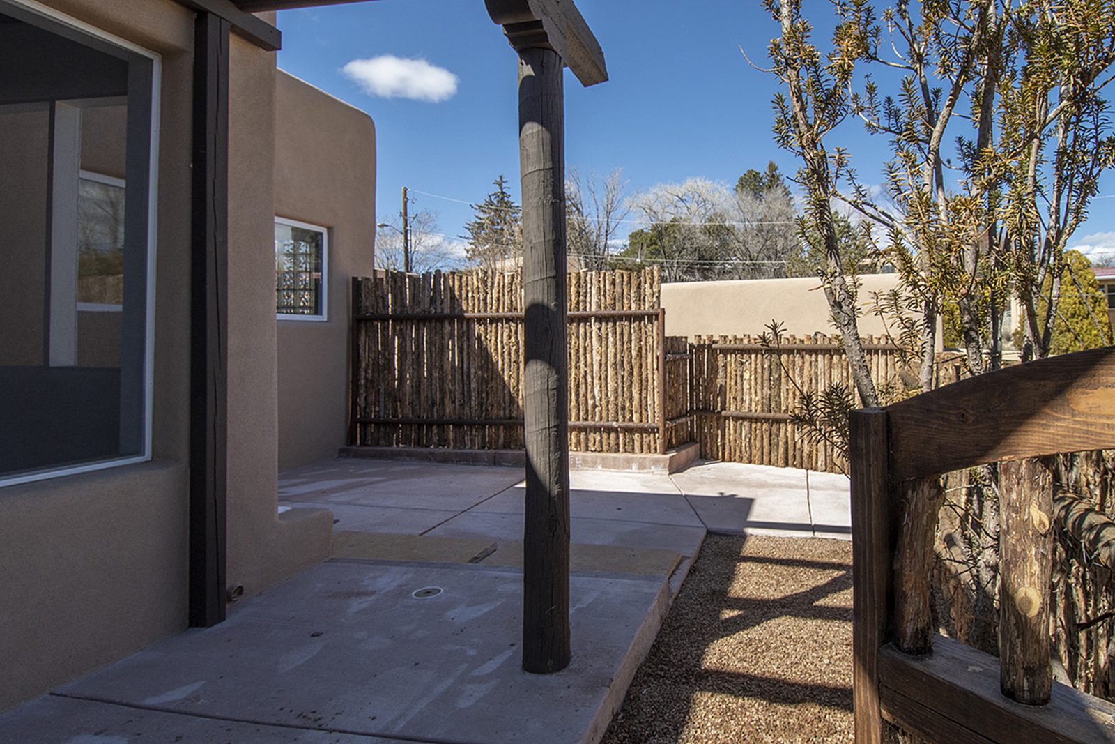 Unit C's front patio, gravel and paving enclosed by coyote-pole fencing.