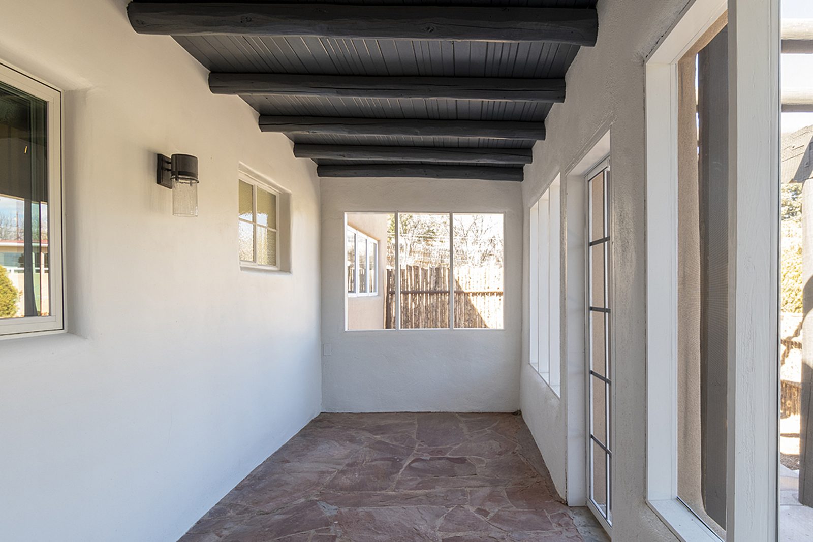 Unit C's screened sun porch, a long room with a corrugated metal ceiling and windows down one side.