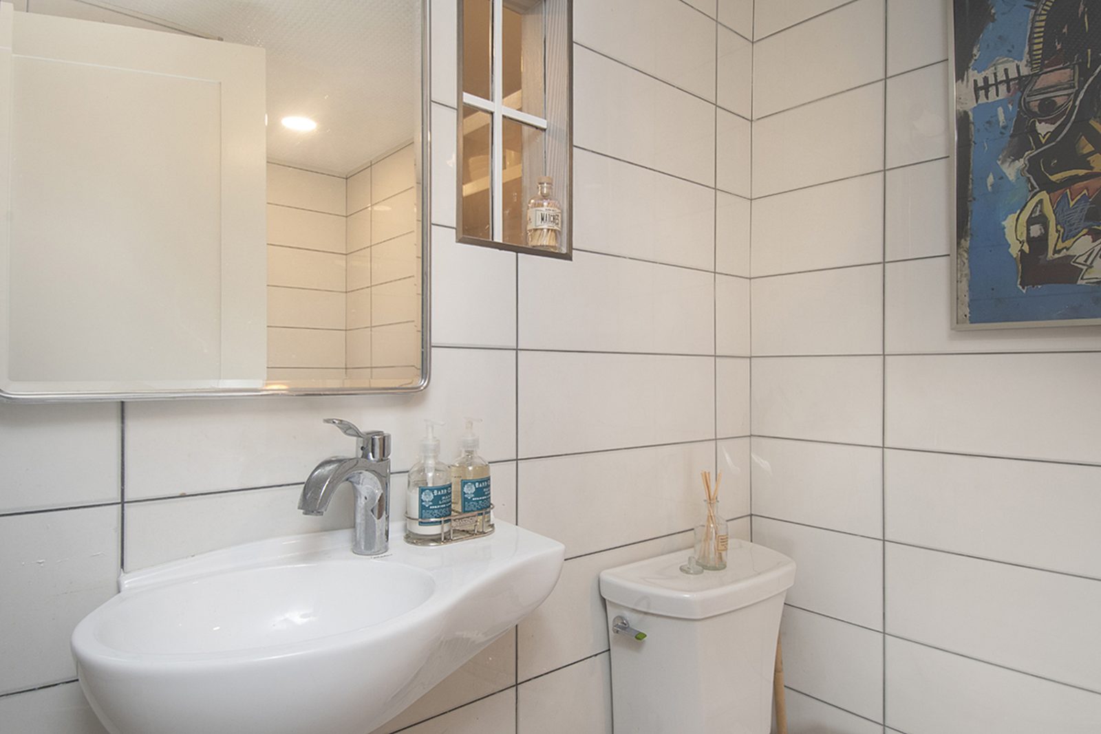 Unit D's bathroom with a wall-mounted sink and white tile.