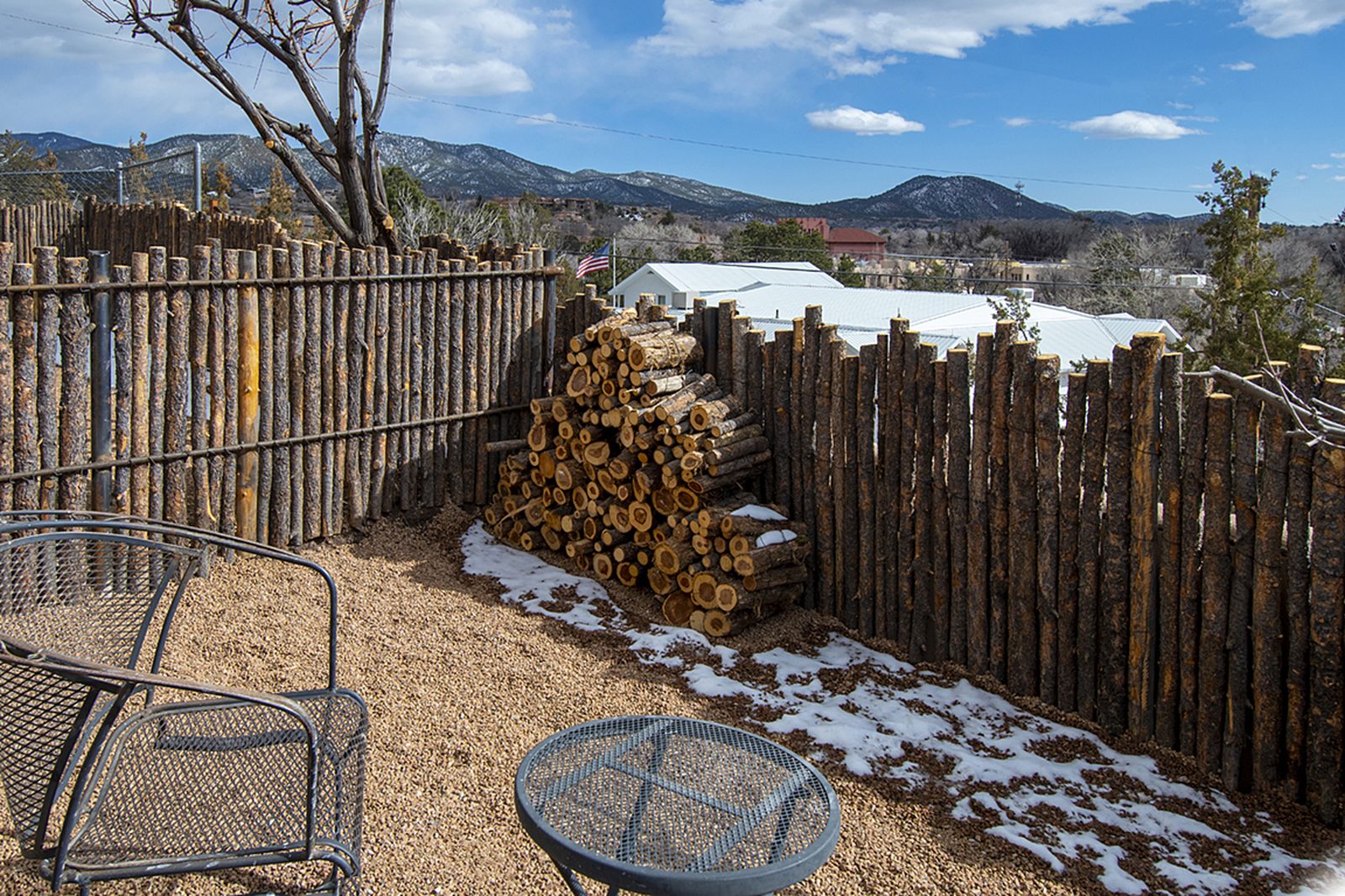 A second look at Unit D's private gated backyard: gravel, metal chairs, coyote-pole fencing and a wide view to the mountains.