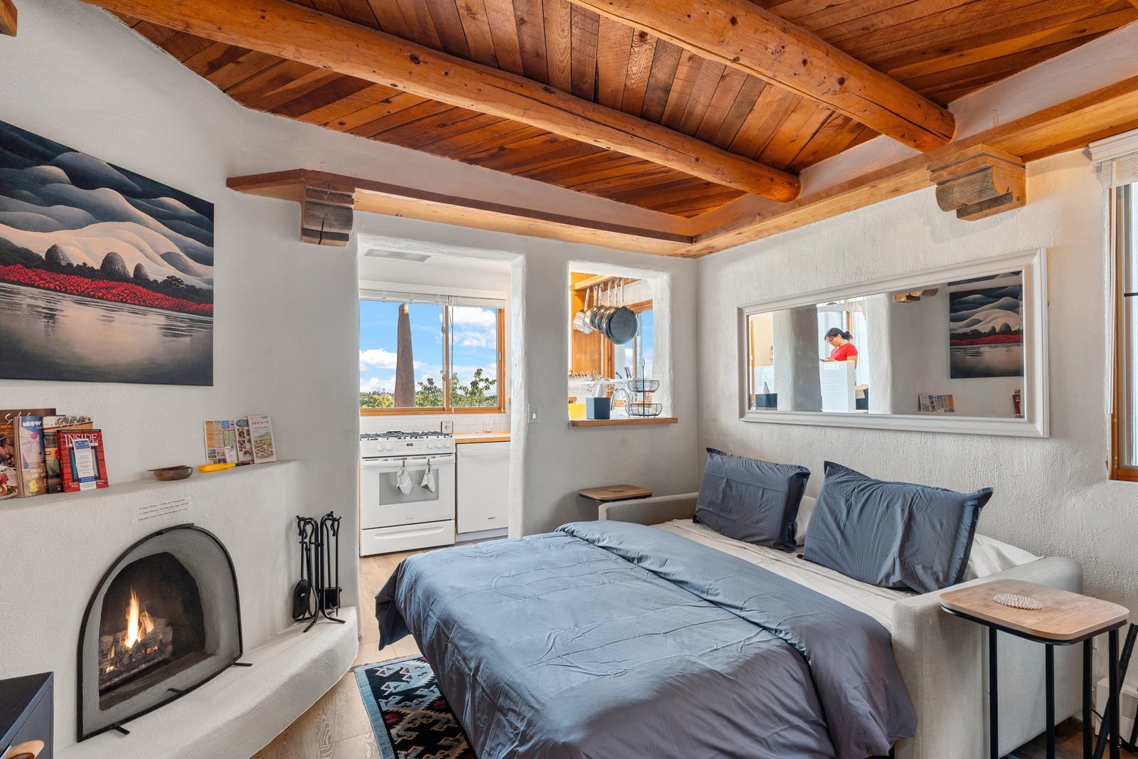 The bed and the kiva fireplace in one frame, showing how the sleeping and living space share the room.