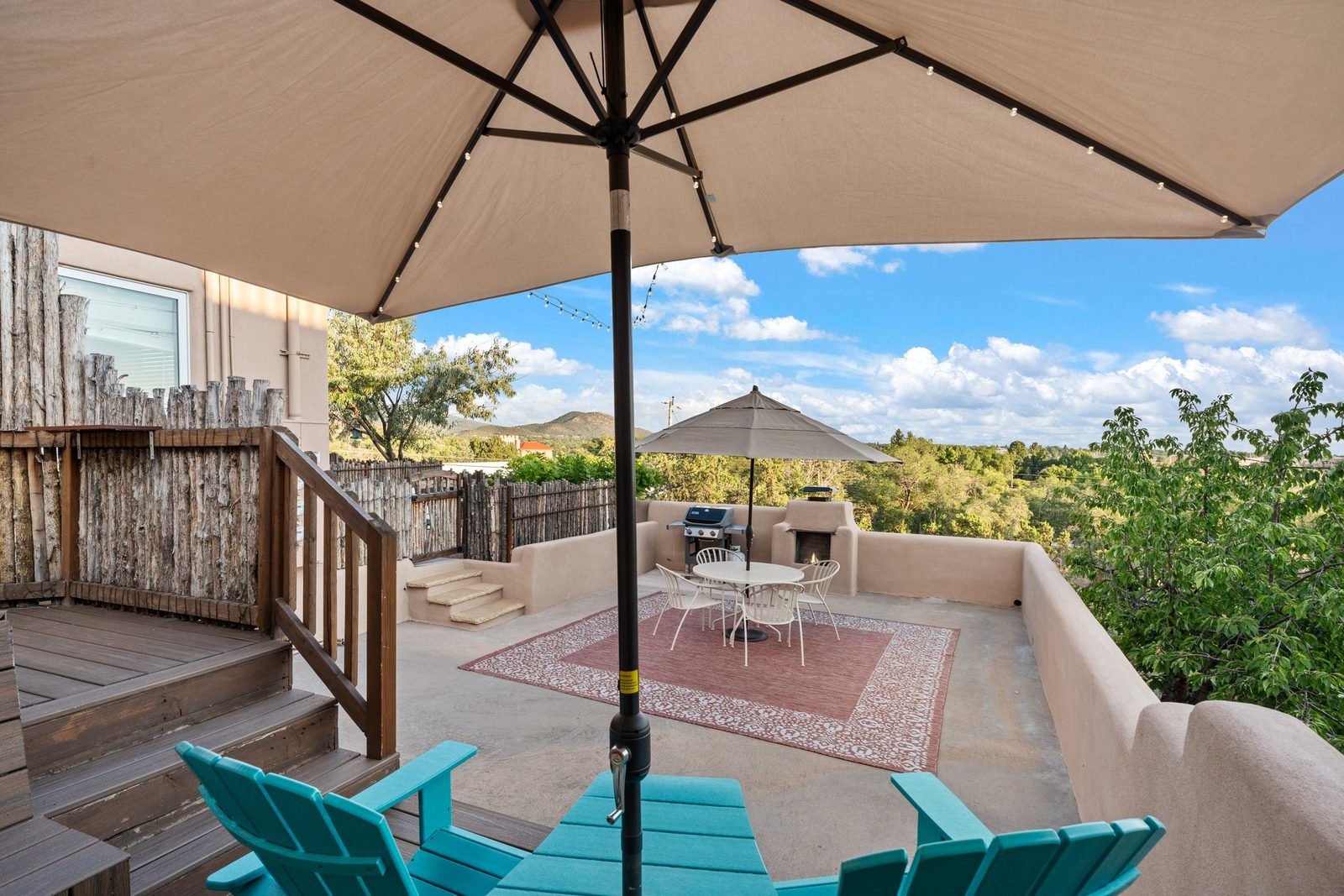 The private deck: umbrellas up, dining table and chairs on the rug, coyote-pole fencing all the way round, and the city below.