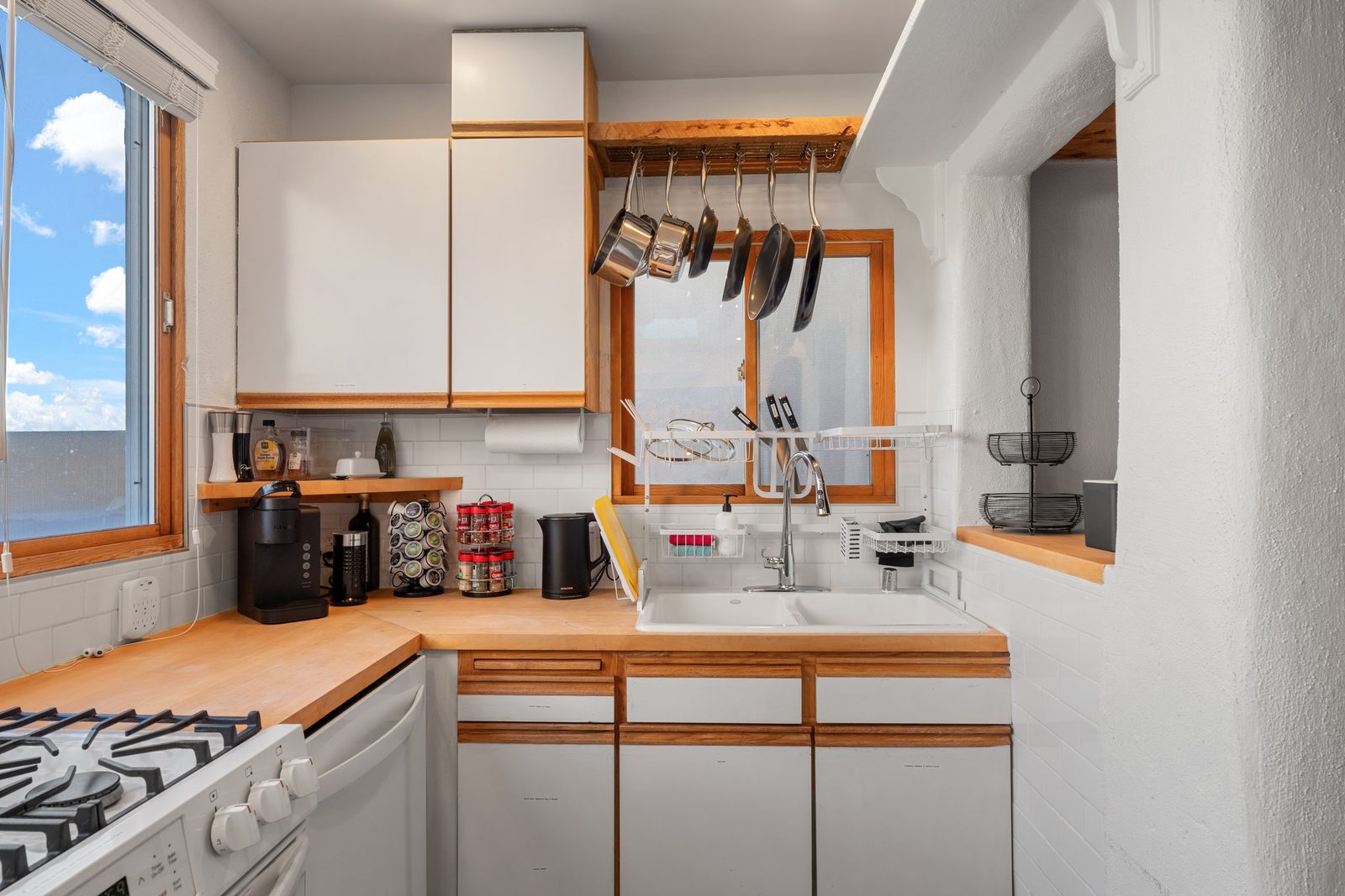 Copper-bottomed pans hung on a rack above the restored wood countertop beside the sink.