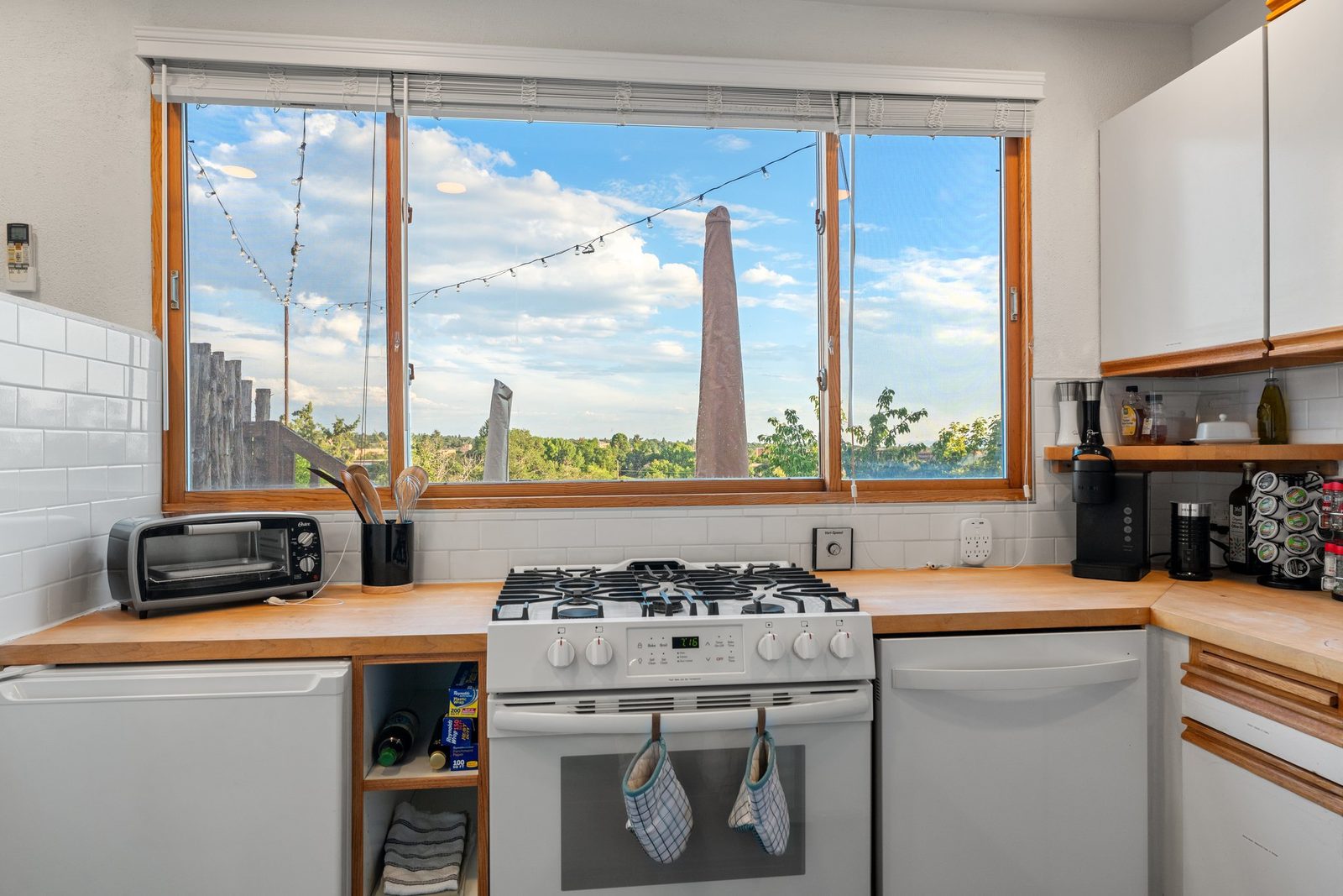 The kitchen counter under a window that runs the length of it, looking out over the treetops.