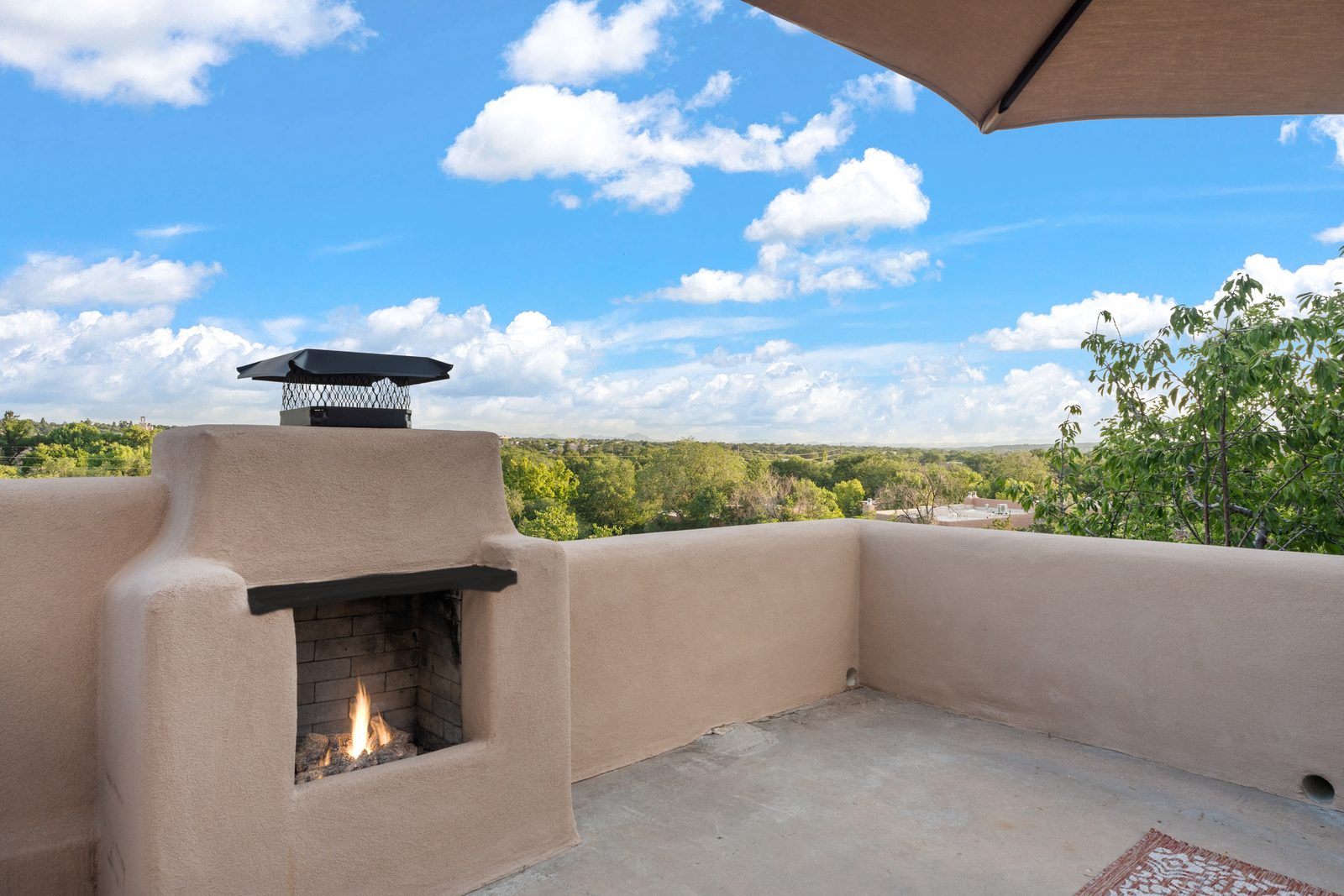 The deck's own outdoor kiva fireplace, lit, with the whole valley and the mountains open behind it.